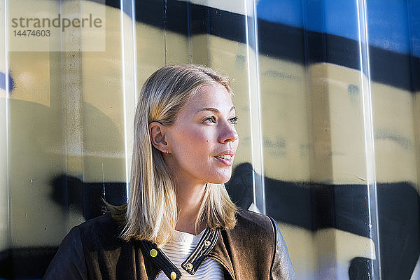 Porträt einer blonden Frau vor einem Container mit Blick aus der Ferne