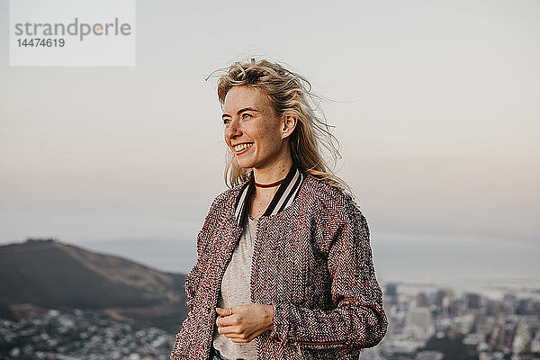 Südafrika  Kapstadt  Kloof Nek  lächelnde Frau an der Küste bei Sonnenuntergang