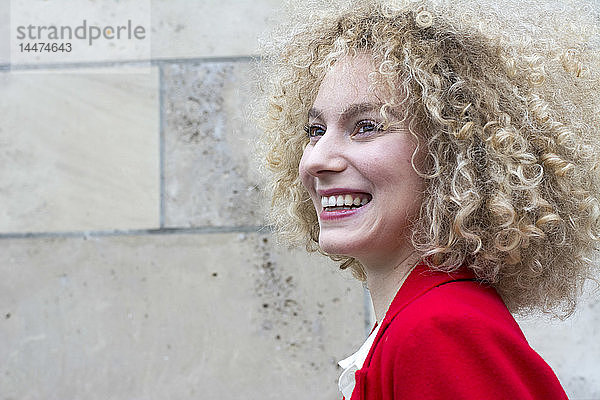 Porträt einer lachenden blonden Frau mit Ringellöckchen