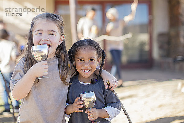 Porträt von zwei glücklichen Mädchen  die aus Kelche trinken