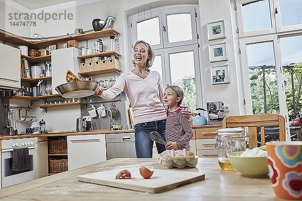 Glückliche Mutter und Tochter backen gemeinsam Pfannkuchen in der heimischen Küche