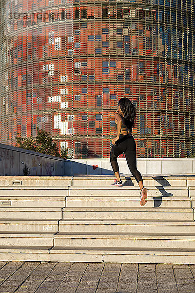 Junge Frau rennt in der Stadt die Treppe hinauf