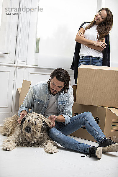 Ehepaar mit Hund und Pappkartons im neuen Zuhause