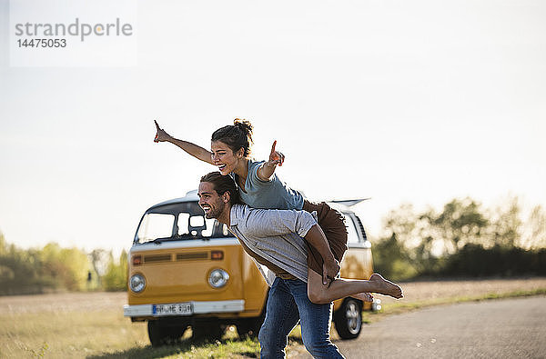 Glückliches Paar macht eine Autoreise mit einem Wohnmobil und gibt vor  auf der Straße zu fliegen