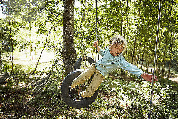 Junge balanciert auf Reifen in einem Abenteuerpark im Wald