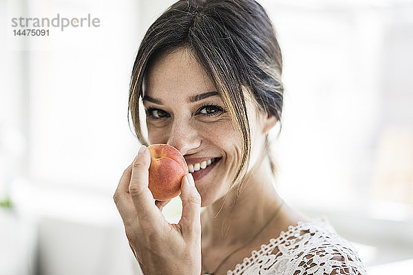 Lachende Frau riecht an einer Aprikose