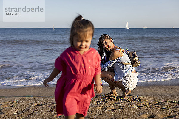 Mutter beobachtet rennende Tochter am Strand