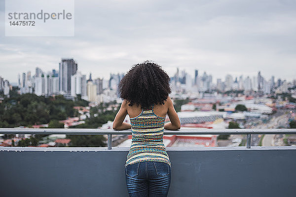 Panama  Panama City  Rückansicht einer jungen Frau  die auf dem Balkon steht und auf die Aussicht schaut