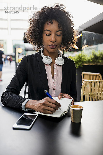 Porträt einer Geschäftsfrau  die sich im Straßencafé Notizen macht