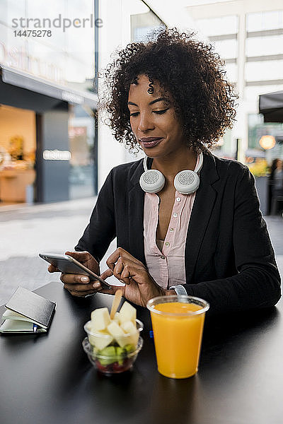 Porträt einer Geschäftsfrau  die ein Mobiltelefon im Straßencafé benutzt