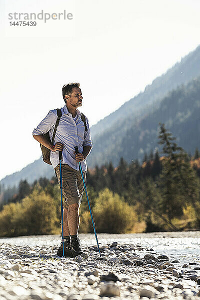 Österreich  Alpen  Mann auf einer Wanderung auf Kieselsteinen an einem Bach stehend