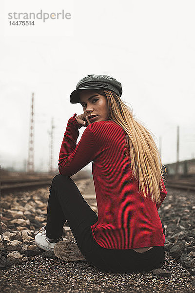 Porträt einer modischen jungen Frau mit Mütze und rotem Pullover im Freien