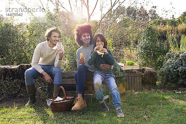 Glückliche Familie sitzt im Garten  macht eine Pause  isst Sandwiches
