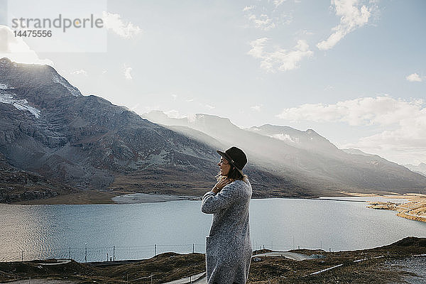 Schweiz  Engadin  Frau steht am Seeufer in einer Berglandschaft