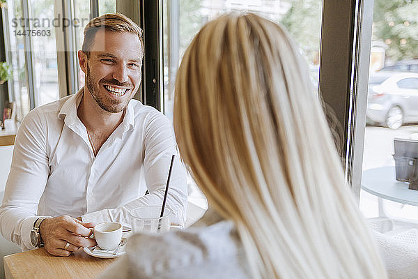 Glücklicher Mann schaut Frau in einem Café an