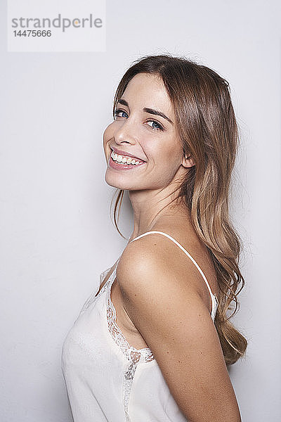 Porträt einer lachenden jungen Frau mit weißem Oberteil
