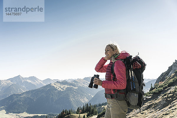 Österreich  Tirol  lächelnde Frau mit Fernglas auf einer Wanderung