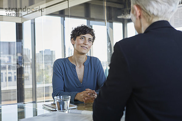 Zwei Geschäftsfrauen unterhalten sich am Schreibtisch im Büro