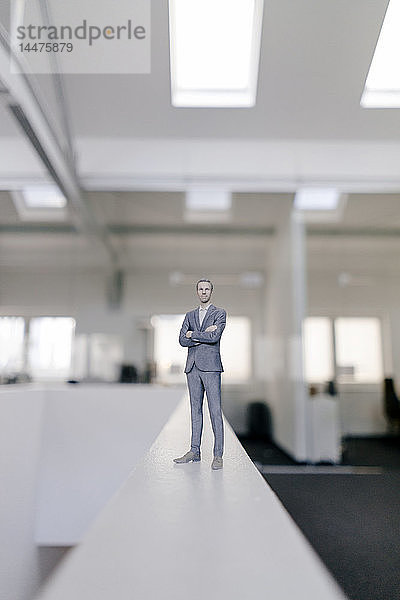 Geschäftsmann-Figur auf Schreibtisch stehend im modernen Büro