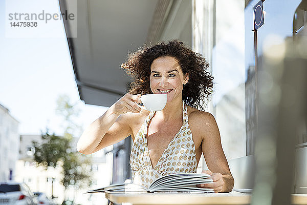 Reife Frau sitzt im Café  liest ein Buch  trinkt Kaffee