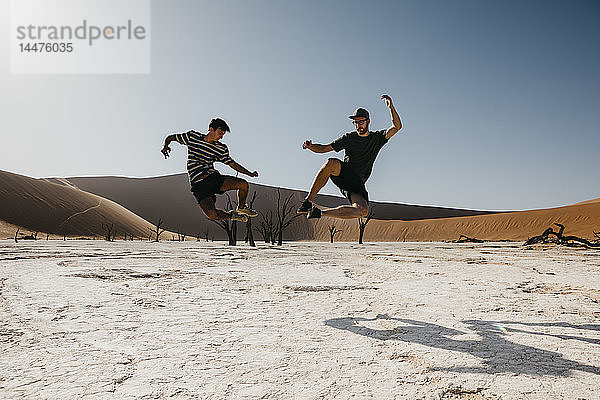 Namibia  Namib-Wüste  Namib-Naukluft-Nationalpark  Sossusvlei  zwei Männer springen in Deadvlei