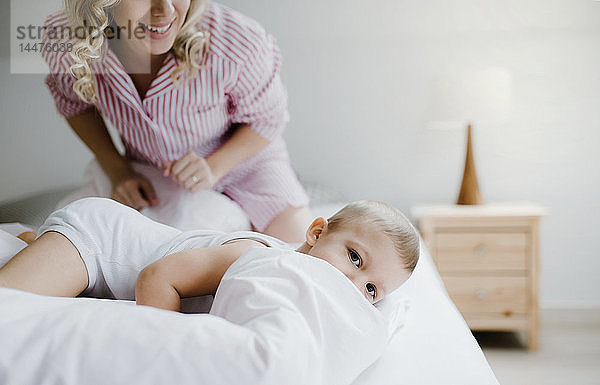 Lächelnde Mutter und Kleinkind-Sohn zu Hause im Bett