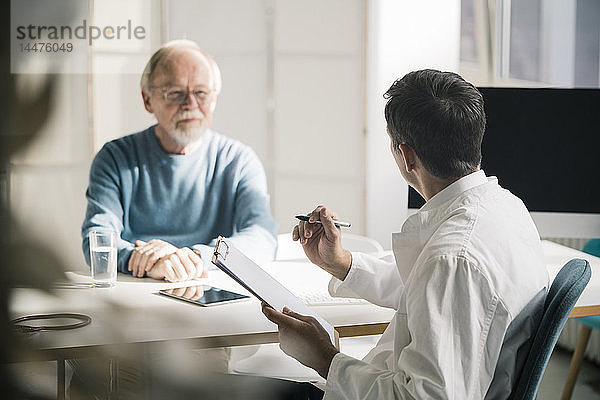 Arzt im Gespräch mit älterem Patienten in medizinischer Praxis