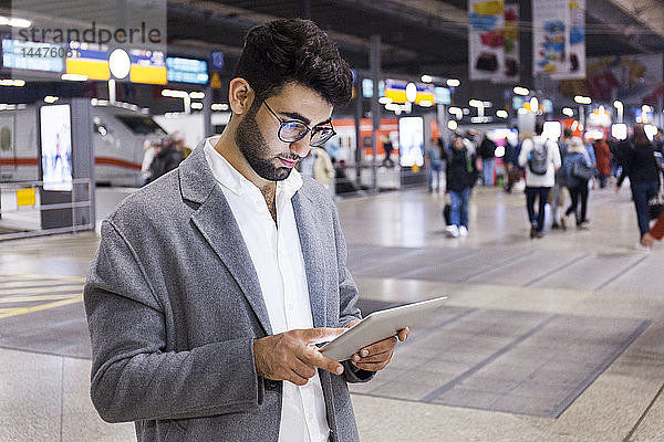 Deutschland  München  junger Geschäftsmann mit digitalem Tablet am Hauptbahnhof