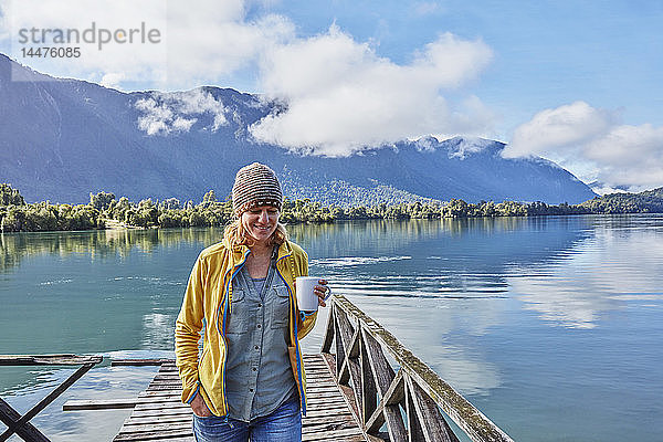 Chile  Chaiten  Lago Rosselot  Frau geht mit Becher auf dem Steg