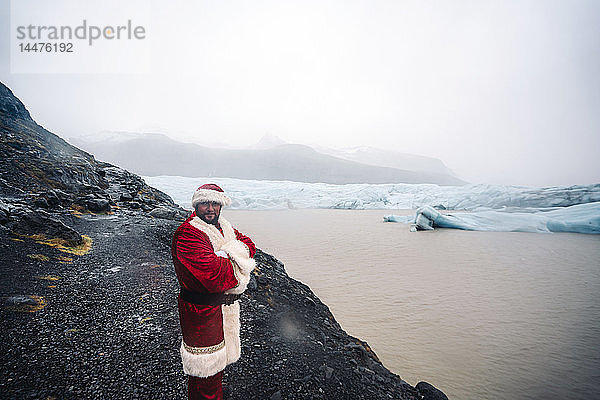 Island  lächelnder Weihnachtsmann vor dem Gletscher stehend