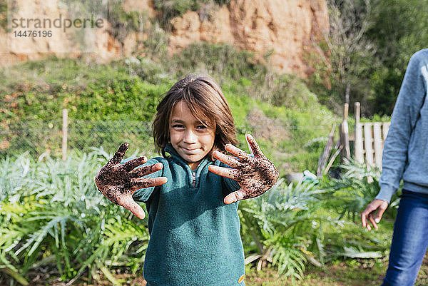 Junge zeigt seine schmutzigen Hände  voller Erde