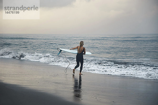 Indonesien  Bali  Strand von Canggu  Surfer mit Surfbrett am Strand