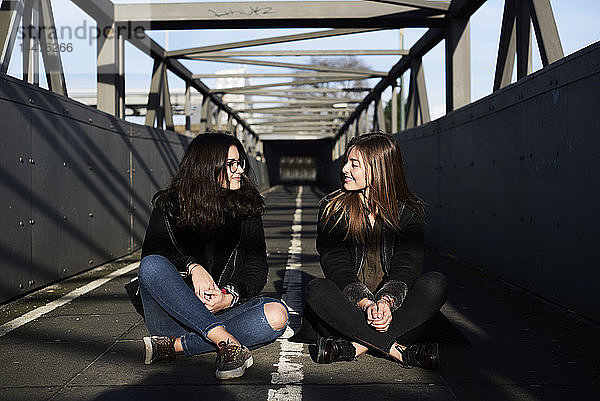 Zwei Freunde sitzen auf einer Brücke und sehen sich an