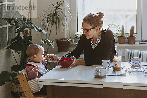 Mutter füttert Baby in der Küche zu Hause