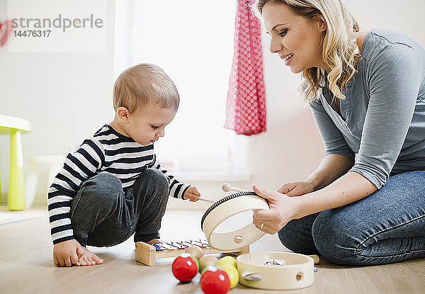 Mutter und Kleinkind spielen zu Hause mit Musikinstrumenten