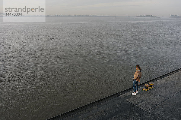Deutschland  Hamburg  Draufsicht auf eine Frau am Elbufer am Pier stehend