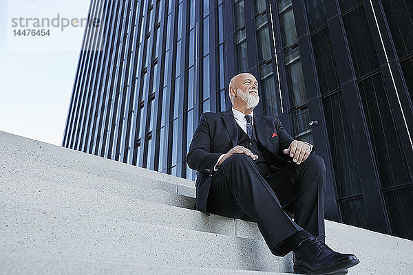Eleganter Geschäftsmann  auf einer Treppe in der Stadt sitzend