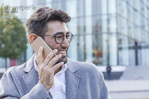 Porträt eines lachenden jungen Geschäftsmannes am Telefon