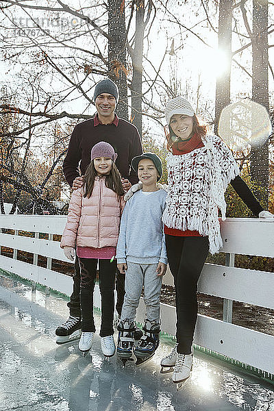 Familie lehnt sich auf dem Geländer der Eisbahn ab