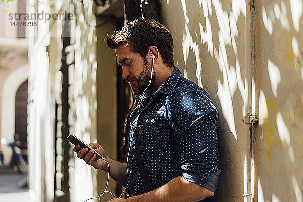 Mann benutzt Kopfhörer und Smartphones im Freien