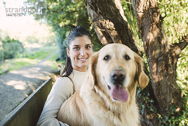 Porträt einer lächelnden jungen Frau mit ihrem Golden-Retriever-Hund