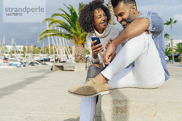 Spanien  Barcelona  glückliches Paar mit Handy im Yachthafen