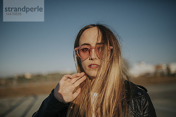 Porträt einer langhaarigen jungen Frau mit Sonnenbrille im Freien