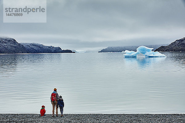 Chile  Torres del Paine Nationalpark  Lago Grey  Frau mit zwei Söhnen steht am Ufer und schaut auf einen Eisberg