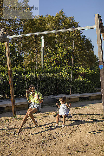 Glückliche Mutter und Tochter auf einer Schaukel auf einem Spielplatz