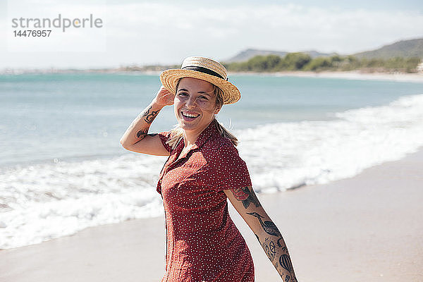 Spanien  Mallorca  Porträt einer glücklichen jungen Frau mit Tätowierungen am Strand