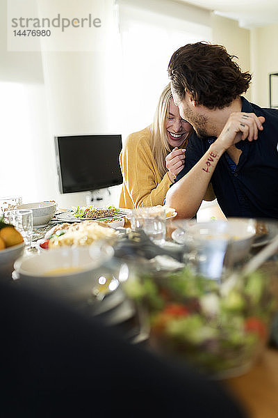 Freunde beim gemeinsamen Mittagessen  liebevolles Paar küsst sich am Tisch