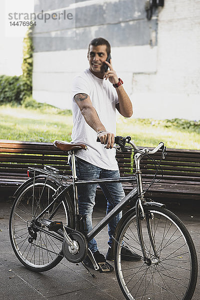 Junger Mann mit Fahrrad und Handy unterwegs
