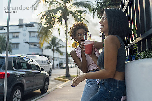 USA  Florida  Miami Beach  zwei glückliche Freundinnen bei einem Erfrischungsgetränk in der Stadt