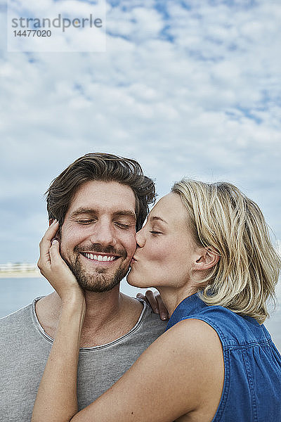 Glückliches junges Paar küsst sich am Strand
